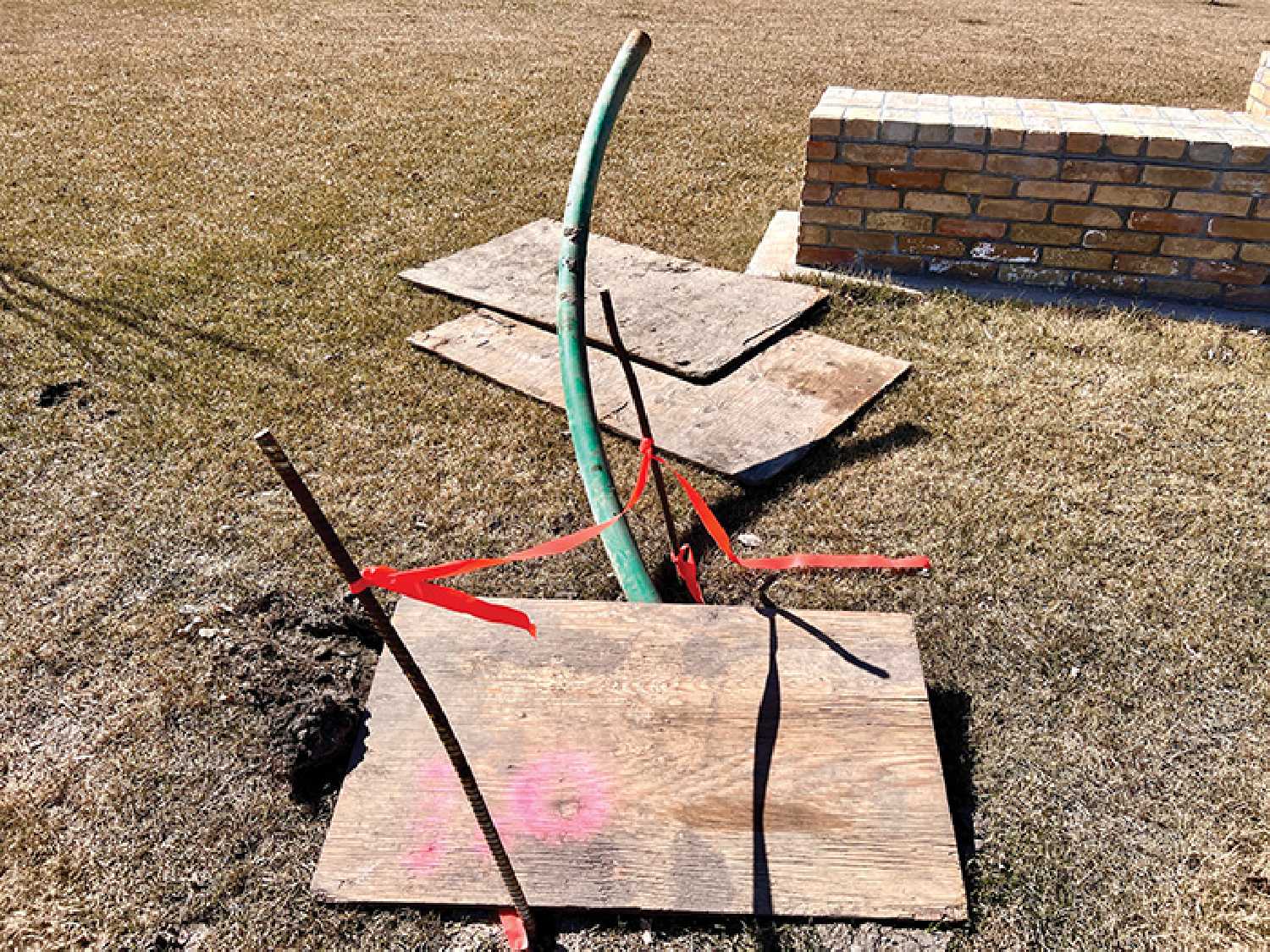 This photo shows rebar and piping sticking out of the ground at Dr. Davidson Park. The holes were filled with gravel and covered with plywood.